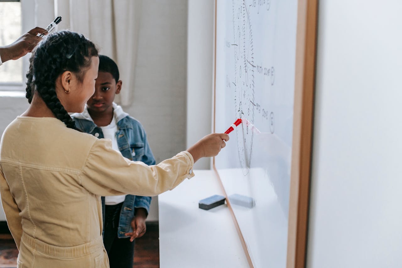 Children engaging in a hands-on learning activity at a whiteboard in a modern classroom setting.